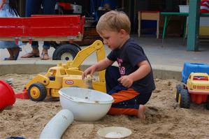 Boy playing in the sandbox with colander